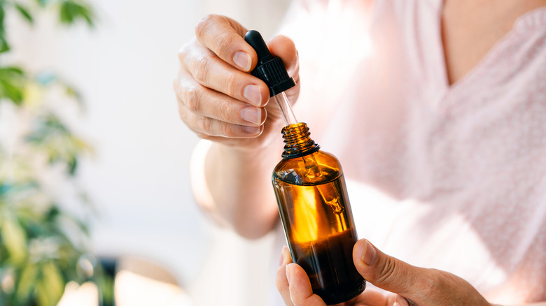 A woman holding a glass container of essential oil