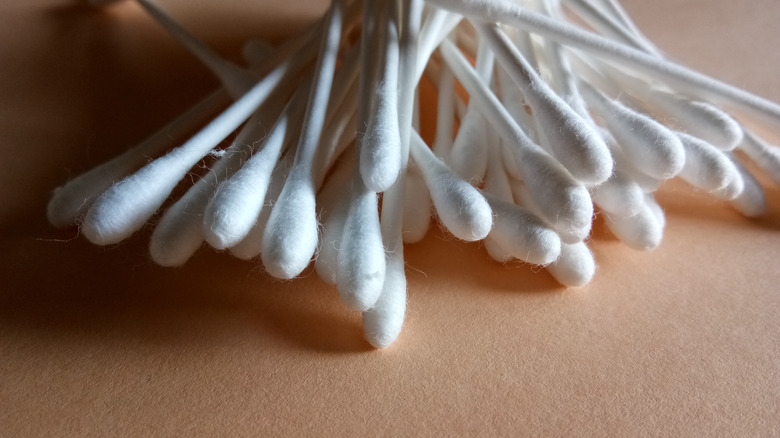 White cotton swabs on a peach-colored background