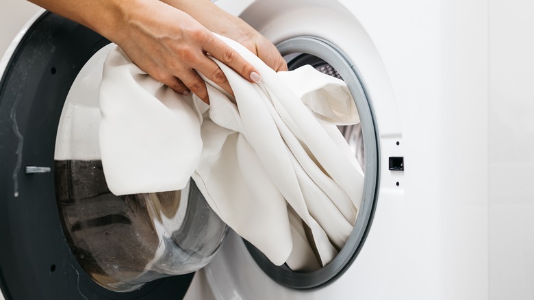 White clothing being placed in a clothing dryer