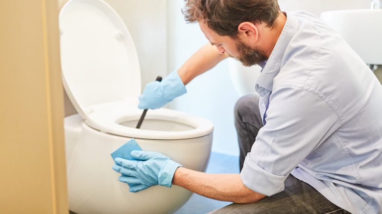 man cleans toilet