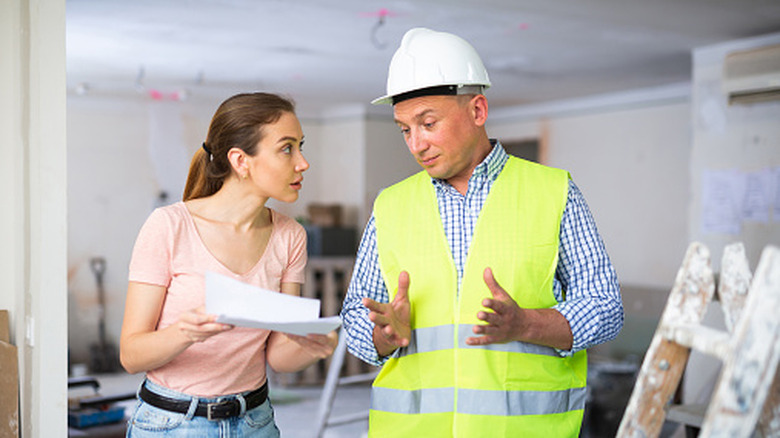 Woman holding a document and speaking with a contractor