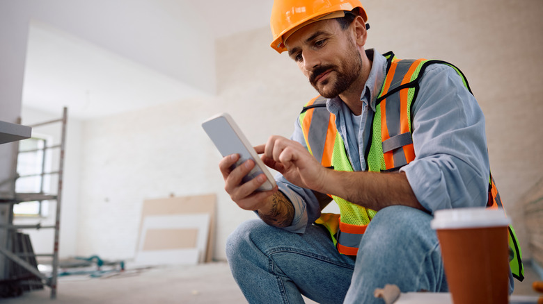 A happy contractor sitting and using his phone