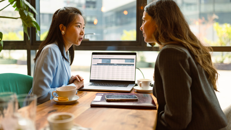 Two women talking with a laptop open on the table