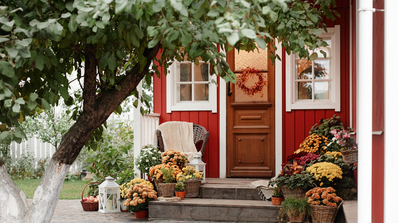 Exterior entryway decorated with chair, flowers, wreath, and lanterns