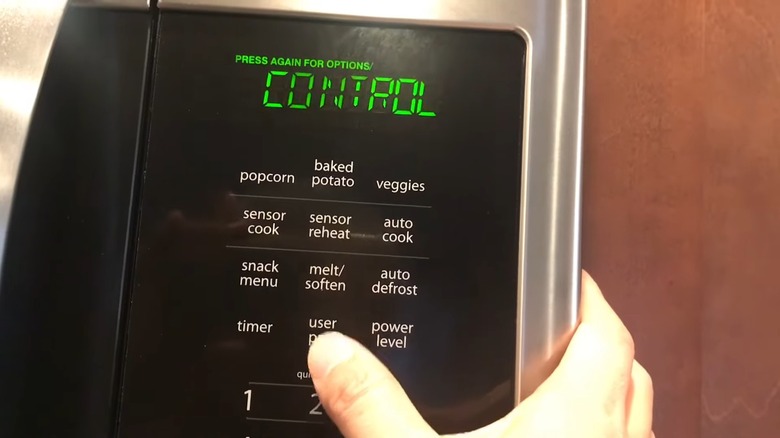 A male hand is pressing the user pref button on a microwave