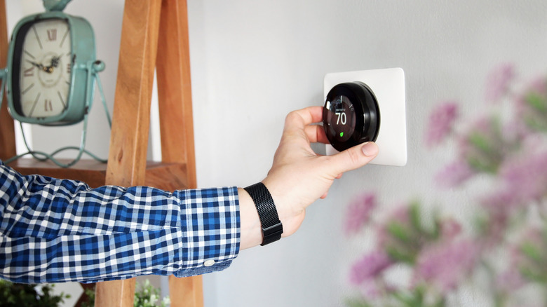 Man adjusting temperature on the thermostat in the living room.