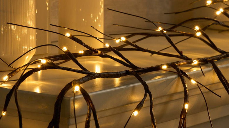 A branch wrapped in black tape with lights and wires attached to it