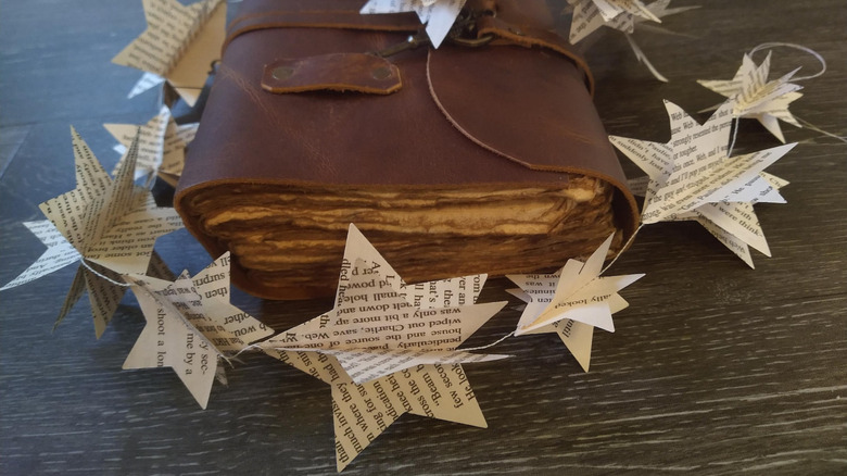A garland with 3D star shapes made from the pages of a book, on top of a journal with thick textured pages