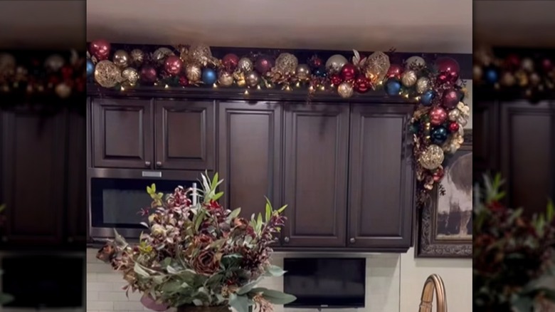 A kitchen with garland on upper cabinets.