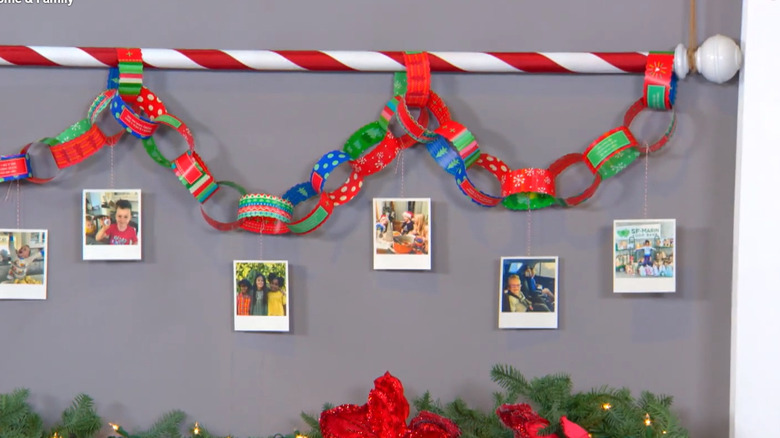 A red and white striped pole with circular paper chains and photos hanging from the wall