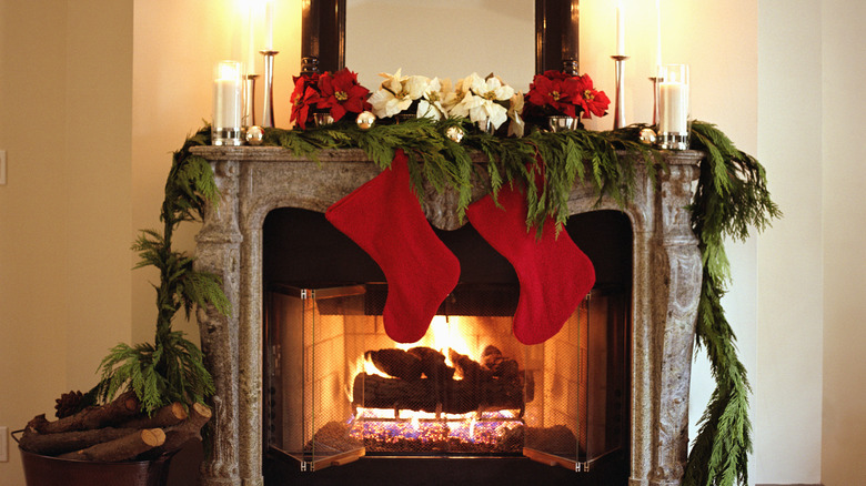 A garland hanging over the fireplace with stockings and poinsettias