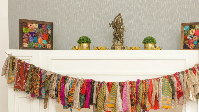 An incredibly colorful garland made from all sorts of different materials hanging above the fireplace