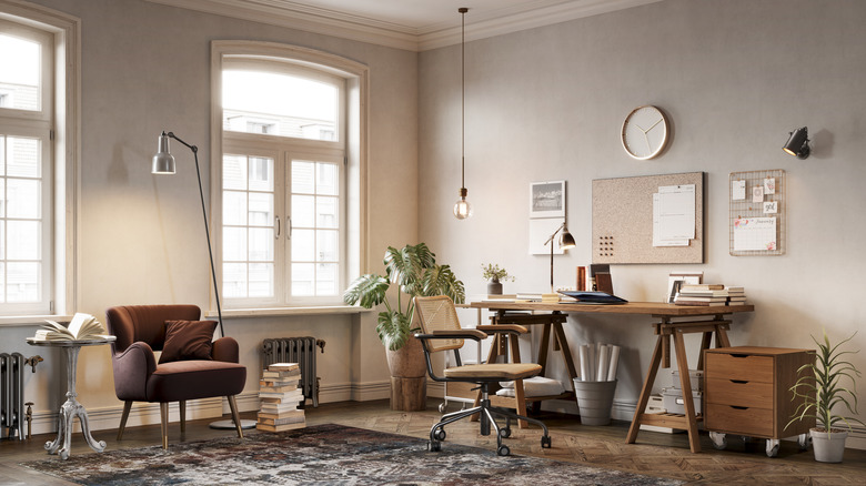 A large office with a desk, office chair and armchair with reading table.