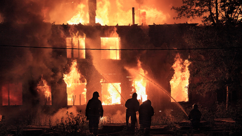 House on fire with firefighters putting out flames