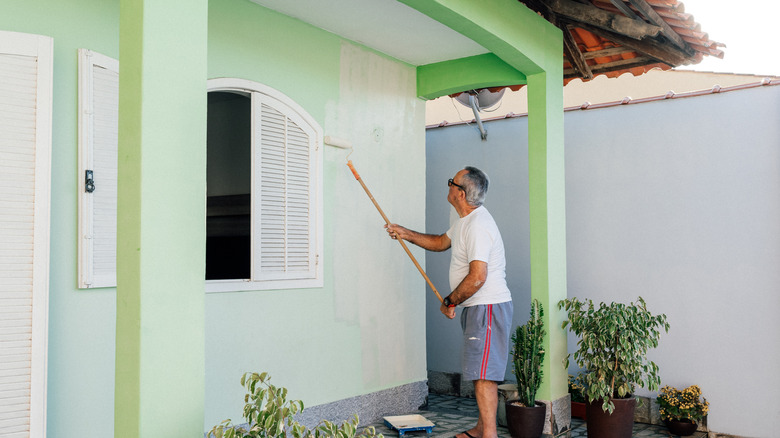 Man painting bright green home facade