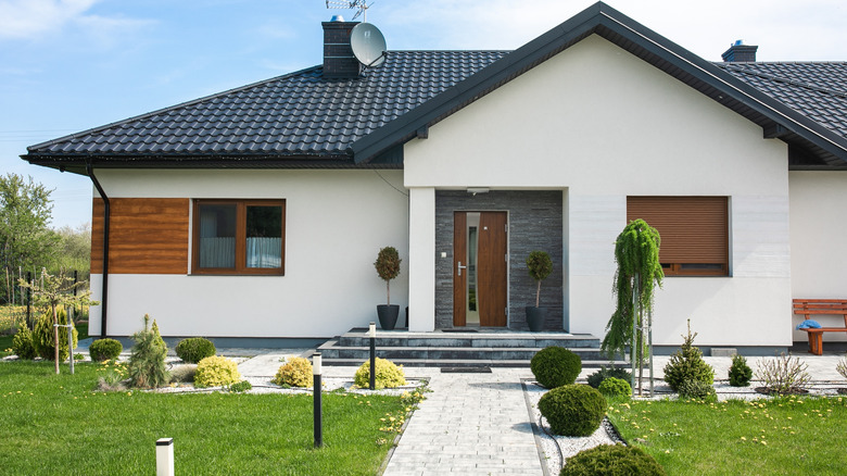 Home with white exterior, black roof, and wooden door