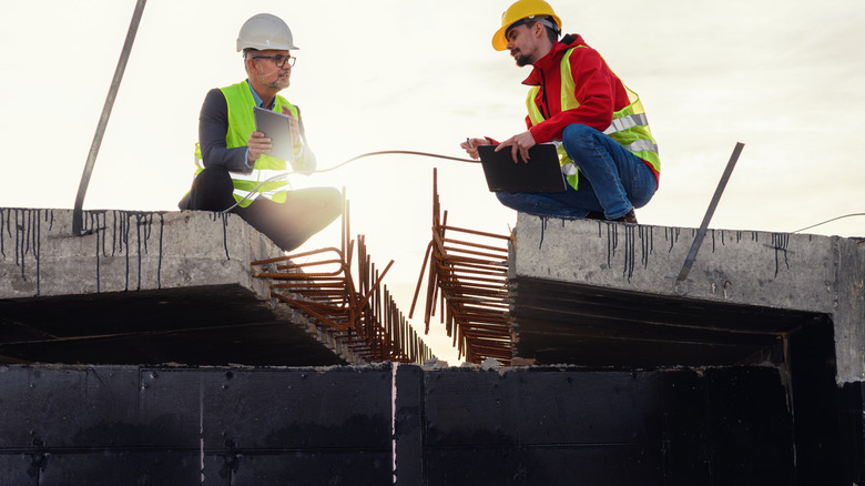 Constructions workers sitting on concrete slabs discussing a project