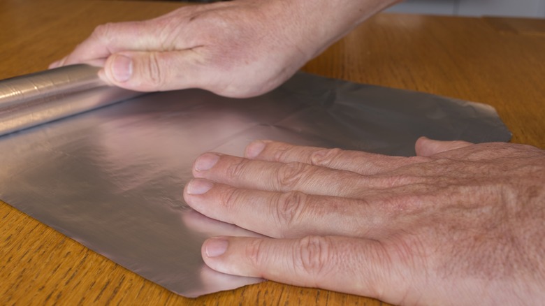Man rolling out aluminum foil