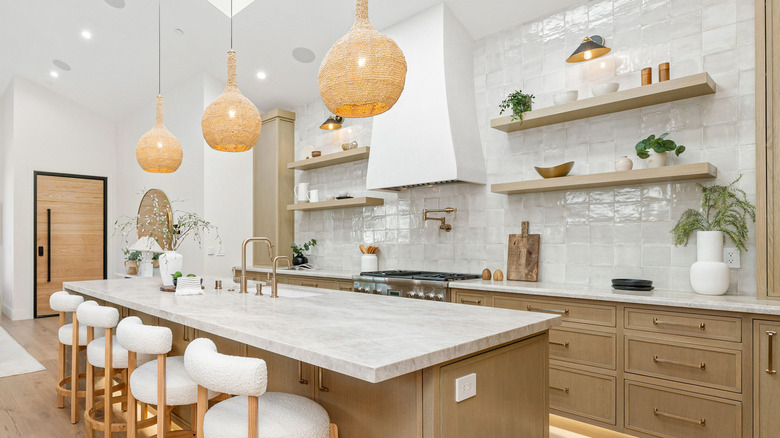 Kitchen with wood cabinets, rattan pendant lights, open shelving, and plants