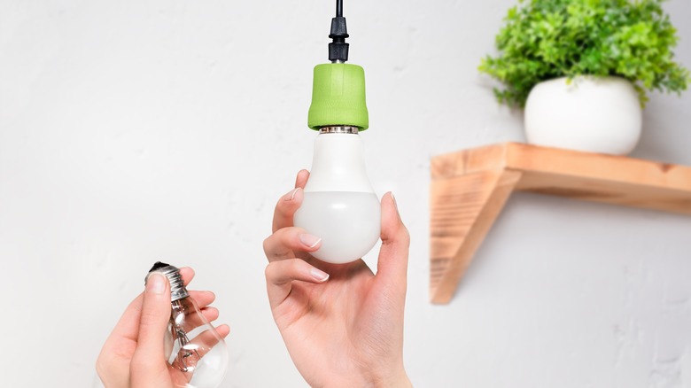 woman switching LED lightbulb 