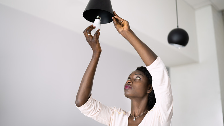 Woman replacing lightbulb in fixture