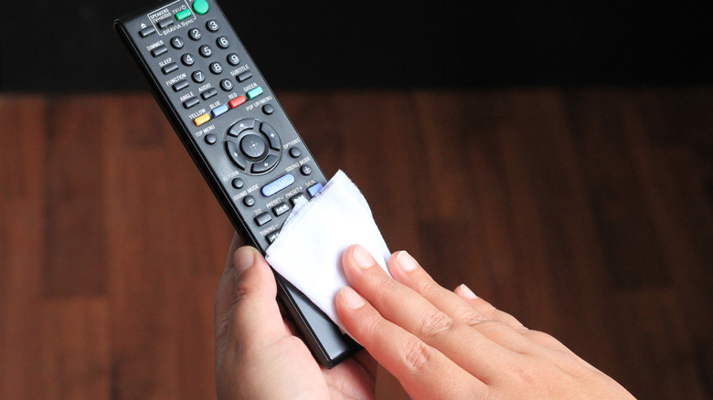 hands using wipe to clean TV remote