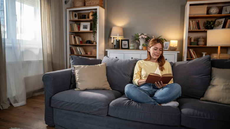 A woman sitting in a living room with gray walls and furniture