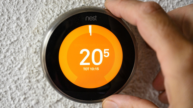 Hand adjusting a Google Nest thermostat