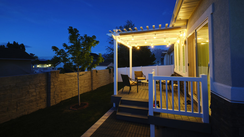 night time view of the back of a home with pergola lighted up with string lights