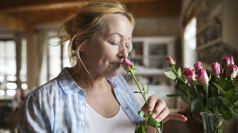 woman sniffs unopened rose