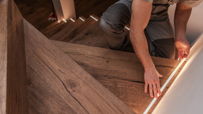 A person measures a step on a staircase to fit it with DIY railings.