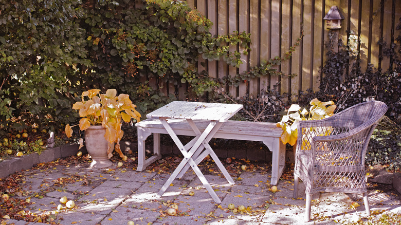 Unkempt patio with dated wood furniture and dead plants