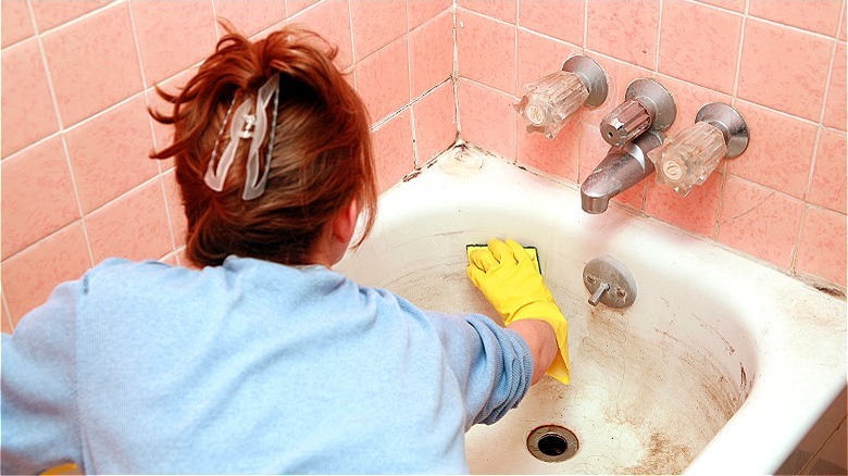 person scrubbing bathtub