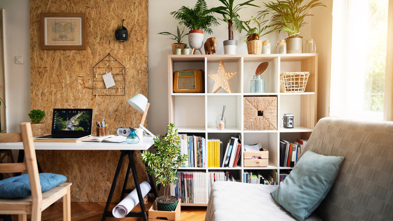A home office with a futon and a cubby-style bookshelf that has books and baskets.