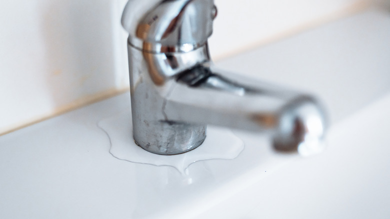 Old bathroom faucet with water seeping from its base