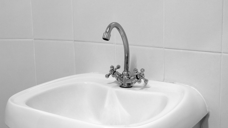 White bathroom sink against white tiled wall backdrop