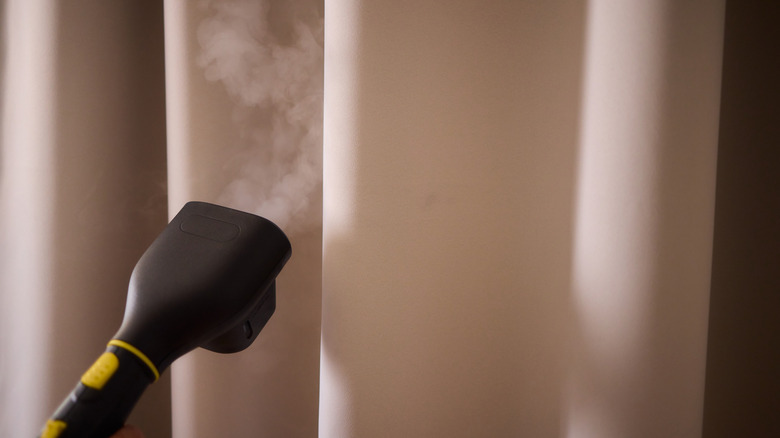 A steam cleaner being used to sanitize a curtain