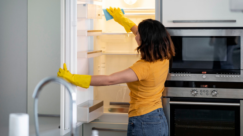 A person in a yellow top cleaning out their fridge