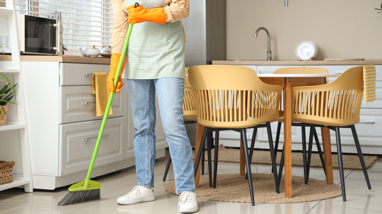 Someone sweeping a white kitchen floor