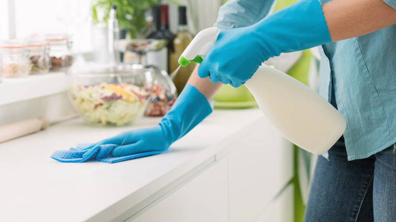 Hands spraying and wiping a cleaner off a kitchen counter