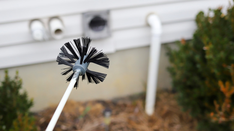 Blurred focus background of a home's exterior, a black cleaning brush in the foreground