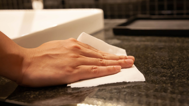 Woman's hand using disinfectant wipe on bathroom counter