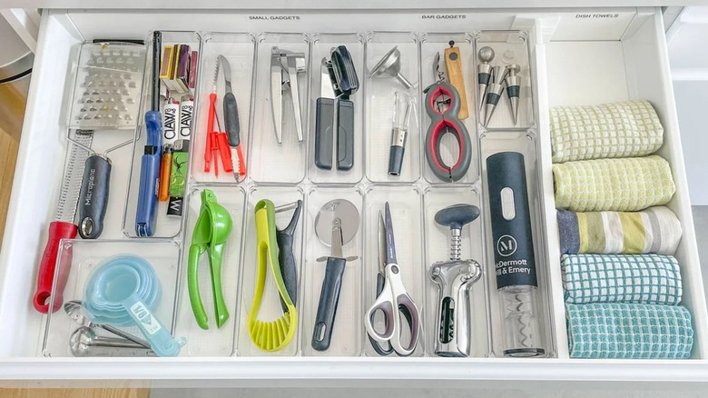Well organized kitchen island drawer with appliances and kitchen towels in storage organizer