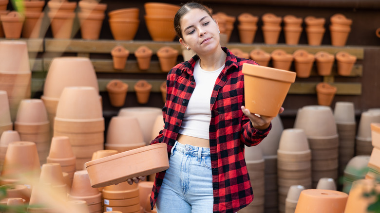 Young woman inspects terra cotta pots.