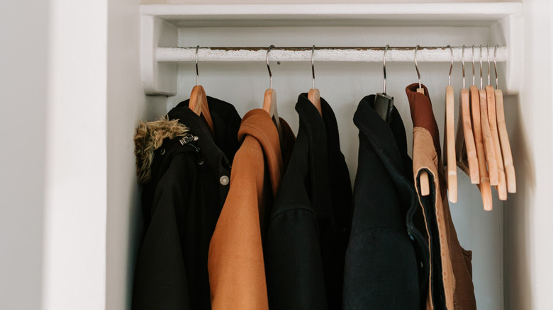 Various winter coats on wooden hanger in closet