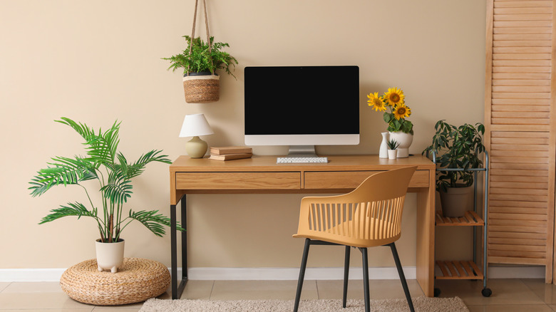 Modern workplace with modern computer, houseplants and sunflowers in room