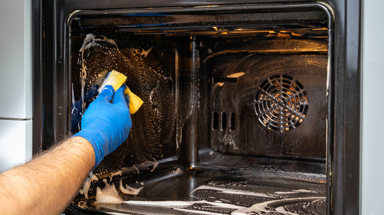A person cleans an oven.