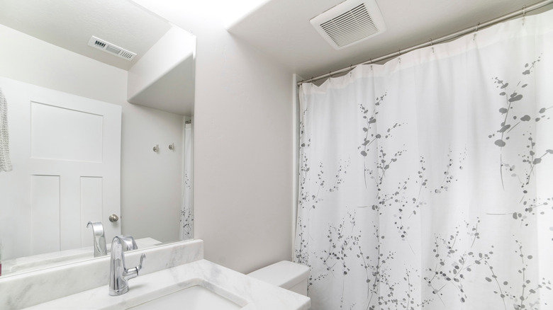 A ventilation fan is visible at the top of a bathroom, near the shower curtain.