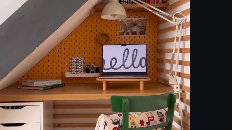 An IKEA pegboard painted yellow is mounted to the wall in a home office space under stairs