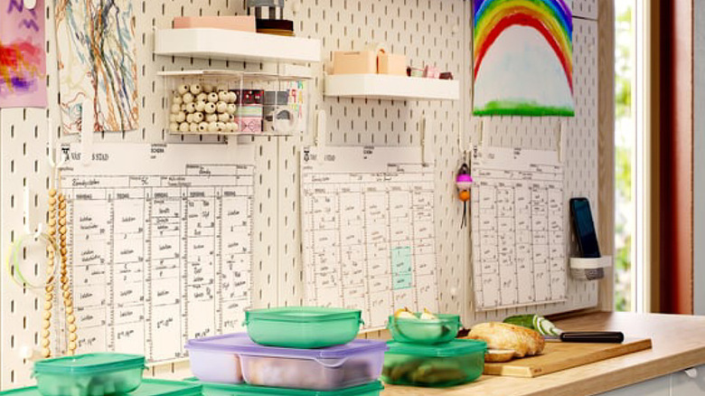 A large IKEA pegboard is set up near a counter, displaying artwork and calendars, and holding supplies in clear bins and on shelves